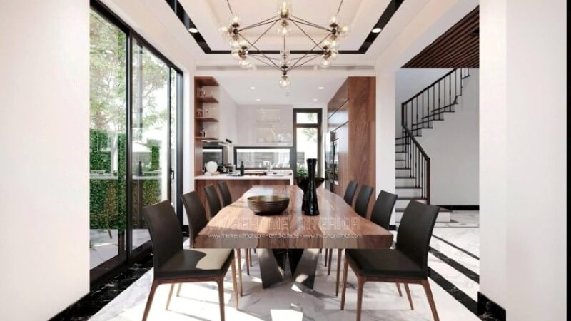 Không chỉ là nơi để mọi người thưởng thức những tinh hoa ẩm thực từ người mẹ, người vợ, người bà,.. mà còn là nơi để gia đình vun đắp nên mái ấm hạnh phúc. Việc chú tâm vào bố trí một không gian phòng ăn biệt thự lại càng được chú trọng để tạo nên điều kiện tốt nhất cho tất cả các thành viên trong gia đình. Việc trang trí, lựa chọn đồ nội thất hợp với lối sống, gu thẩm mỹ và bố trí ánh sáng lại ngày càng được chú trọng. Tùy từng sở thích của mỗi mái ấm mà sẽ có những ý tưởng bố trí nội thất phòng ăn phù hợp chẳng hạn với mẫu thiết kế nội thất phòng ăn phong cách hiện đại trong biệt thự Vinhomes Imperia Hải Phòng. Chất liệu gỗ đặc biệt là gỗ óc chó được thể hiện liền mạch dọc tầm nhìn khi vào từ phòng khách, chiếc bàn gỗ óc chó nguyên khối, chiếc ghế bọc da sử dụng khung gỗ óc chó, dóng sang hai bên là tủ bếp gỗ óc chó, cùng kệ để đồ bắt mắt. Thiết kế nội thất